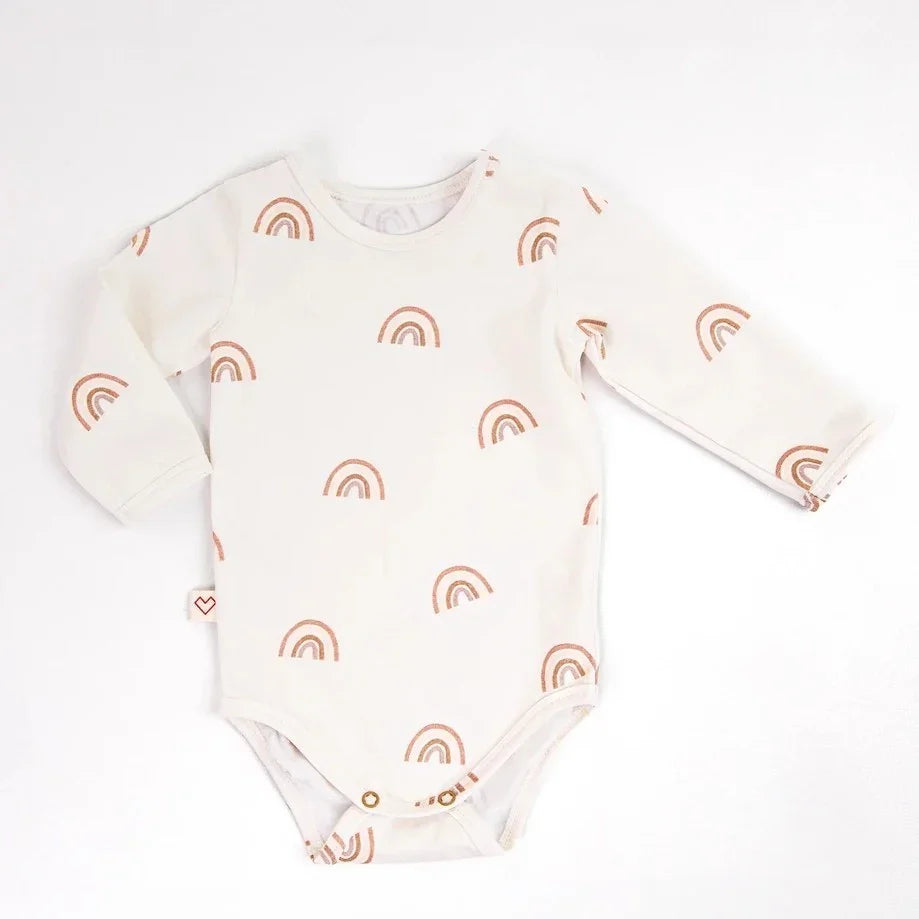 Body para bebé en color crema con mangas largas y patrón de arcoíris marrón, cierre con broches.