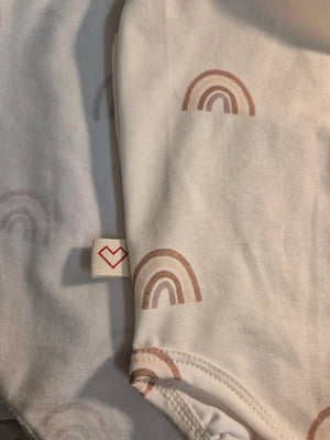 Body blanco suave para bebé con estampado de arcoíris beige y etiqueta de corazón, material de algodón.