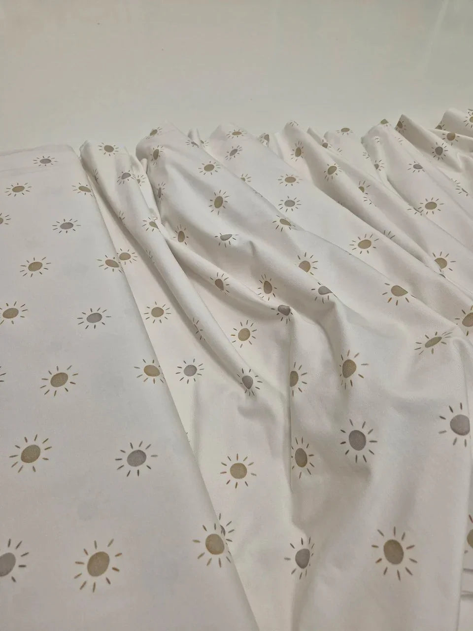 Tela de body de algodón blanco para bebé con patrón de estampado de sol minimalista.
