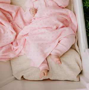 Couverture bébé en tricot rose en coton bio dans un berceau blanc avec motif délicat