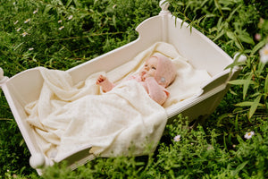 Bébé fille avec tricot rose et couverture crème en tricot dans un berceau blanc en extérieur
