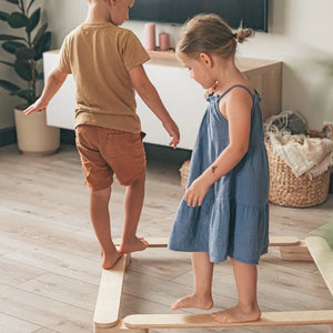 Niños jugando en interiores sobre set de vigas de equilibrio de madera natural, juguete Montessori para niños pequeños