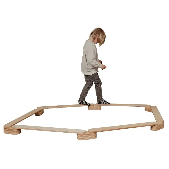 Niño caminando sobre set de vigas de equilibrio de madera, acabado natural, equipo para juego interior
