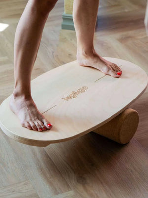 Tabla de equilibrio de madera con rodillo de corcho para ejercicio físico sobre suelo de madera dura