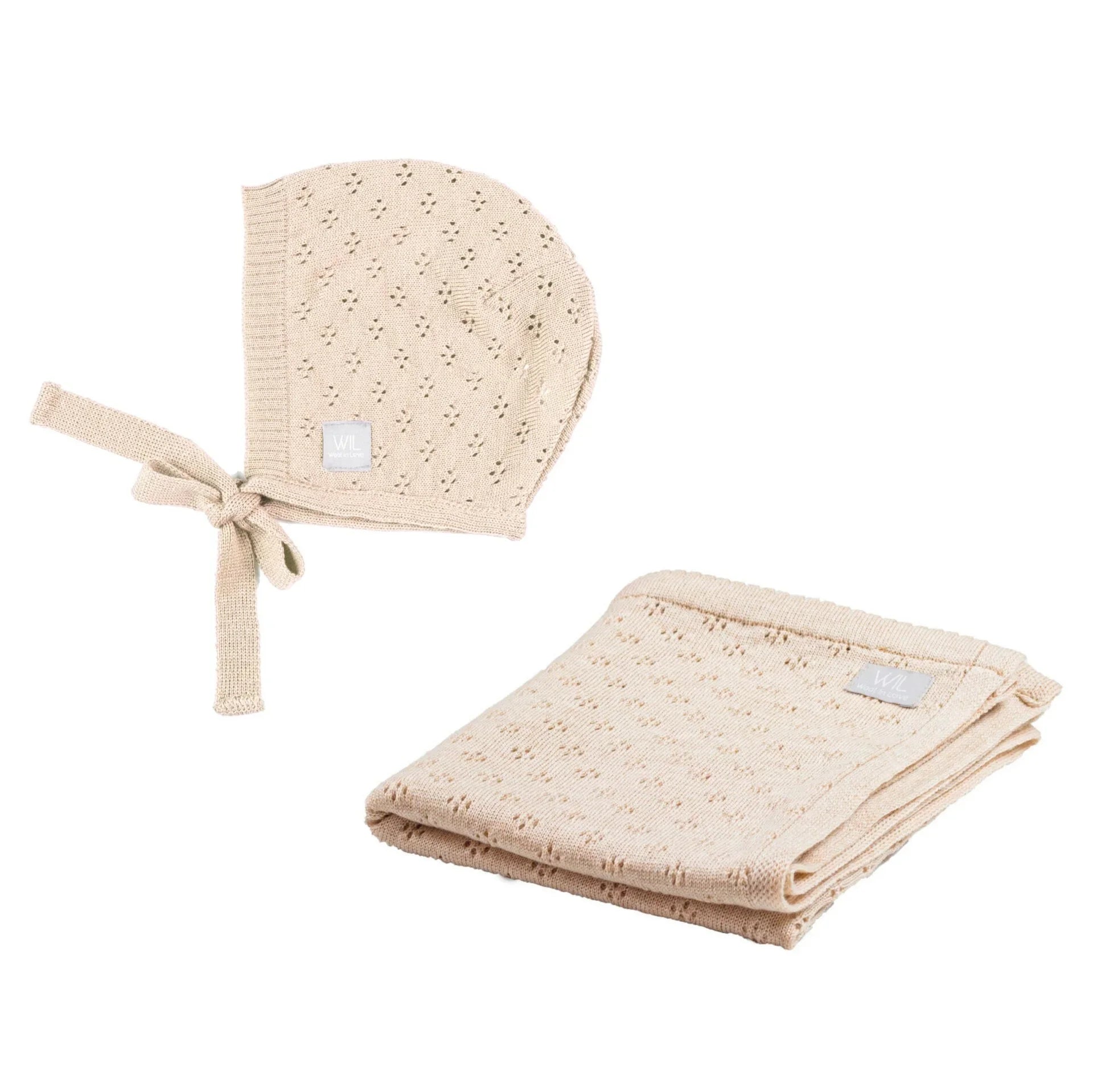 Beige knitted baby bonnet and blanket set with delicate eyelet pattern, folded and side by side