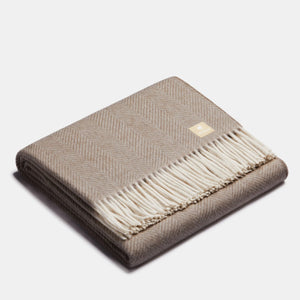 Jeté en laine d'alpaga beige et blanc à motif chevrons, plié, avec franges blanches et étiquette de marque ALPAKA