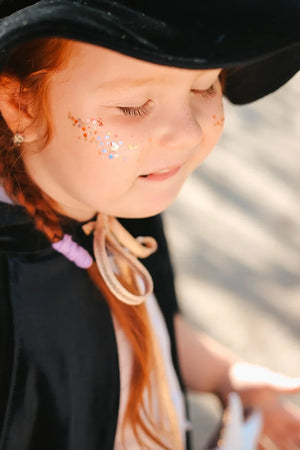 Close-up of child in black velvet cape and witch hat with gold tie detail