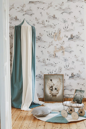 Blue and cream canopy styled with an ocean wallpaper, framed artwork, toy trolley and quilted floor mat