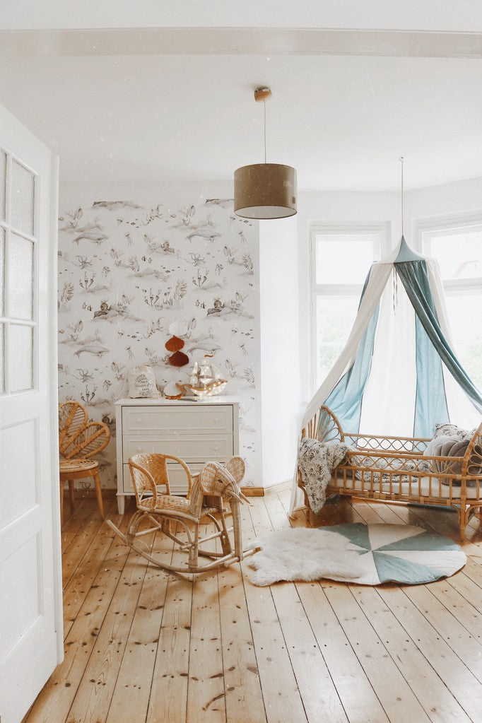 Wide ocean-themed nursery with the Blue Circus canopy above a rattan bed and wooden rocking horse