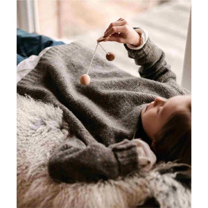 Child lying on a blanket playing with Wooden Story Bon Bon Ball rhythm toy