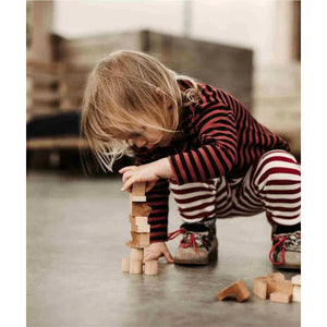 Enfant empilant des blocs en bois naturel lors d'un jeu Montessori, favorisant la motricité fine, l'équilibre, la créativité et l'apprentissage sans écran.