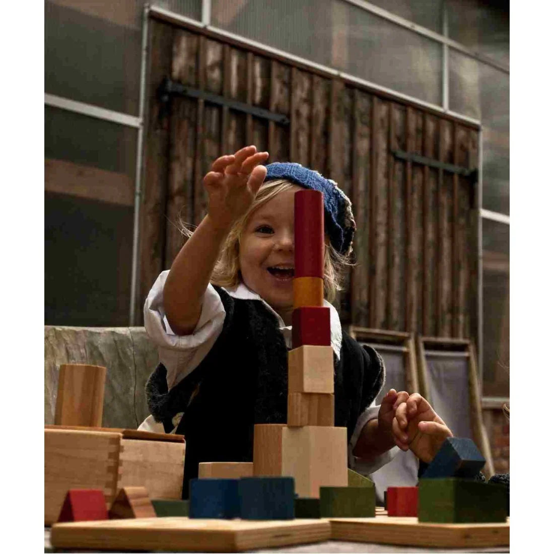 Child stacking colourful Wooden Story wooden building blocks during creative construction play