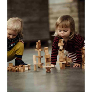 Children playing with natural wood building blocks on concrete floor, creative nursery toy