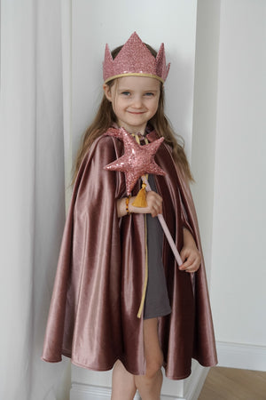 Child wearing the Cosmic Pearl magic cape with a pink crown and star wand during indoor dress-up play