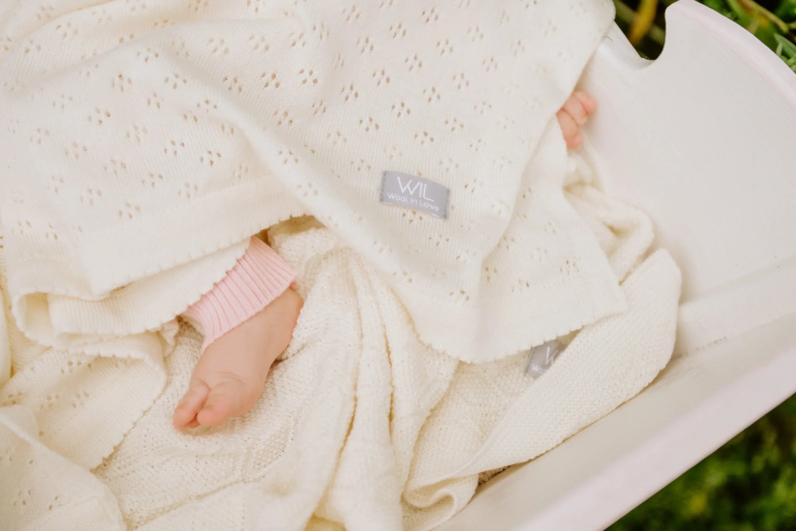 Couverture bébé en tricot crème avec motif œillet délicat, coton bio doux dans le berceau