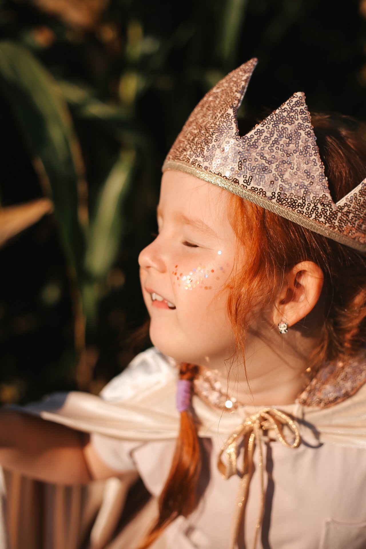 Close-up of a child wearing the Cream Pearl cape with a sparkling rose-gold crown