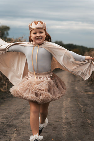 Child running outdoors with arms extended while wearing the Cream Pearl cape and crown