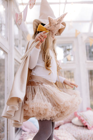 Child wearing the cream velour magic cape with a pointed hat and sparkling star wand