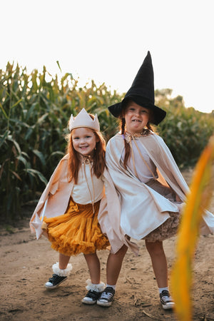 Two children wearing Cream Pearl capes with crown and witch-hat costumes outdoors