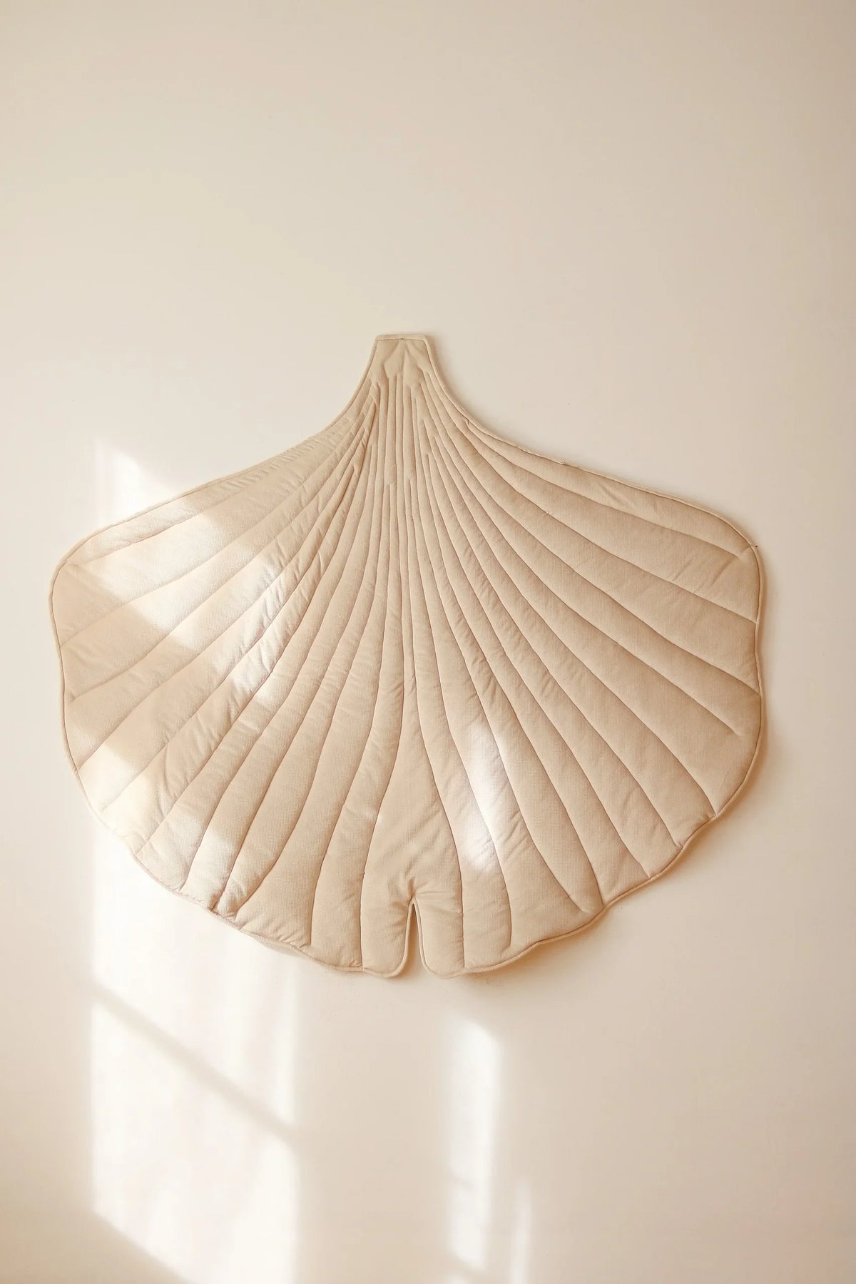Close lifestyle view of cream quilted Ginkgo Leaf Mat displayed on a softly lit wall