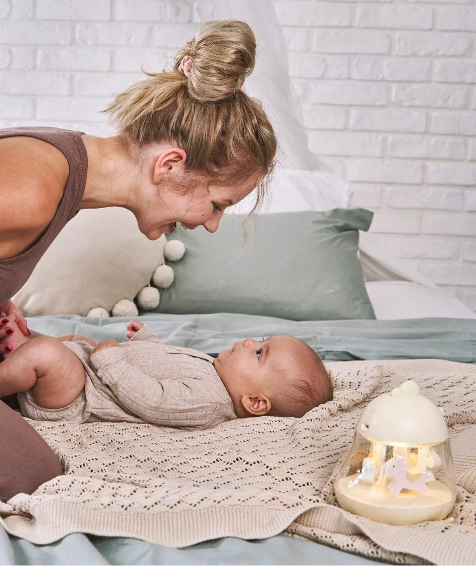 Baby liegt auf beiger Strickdecke mit Nachtlicht und sanfter Pastell-Deko