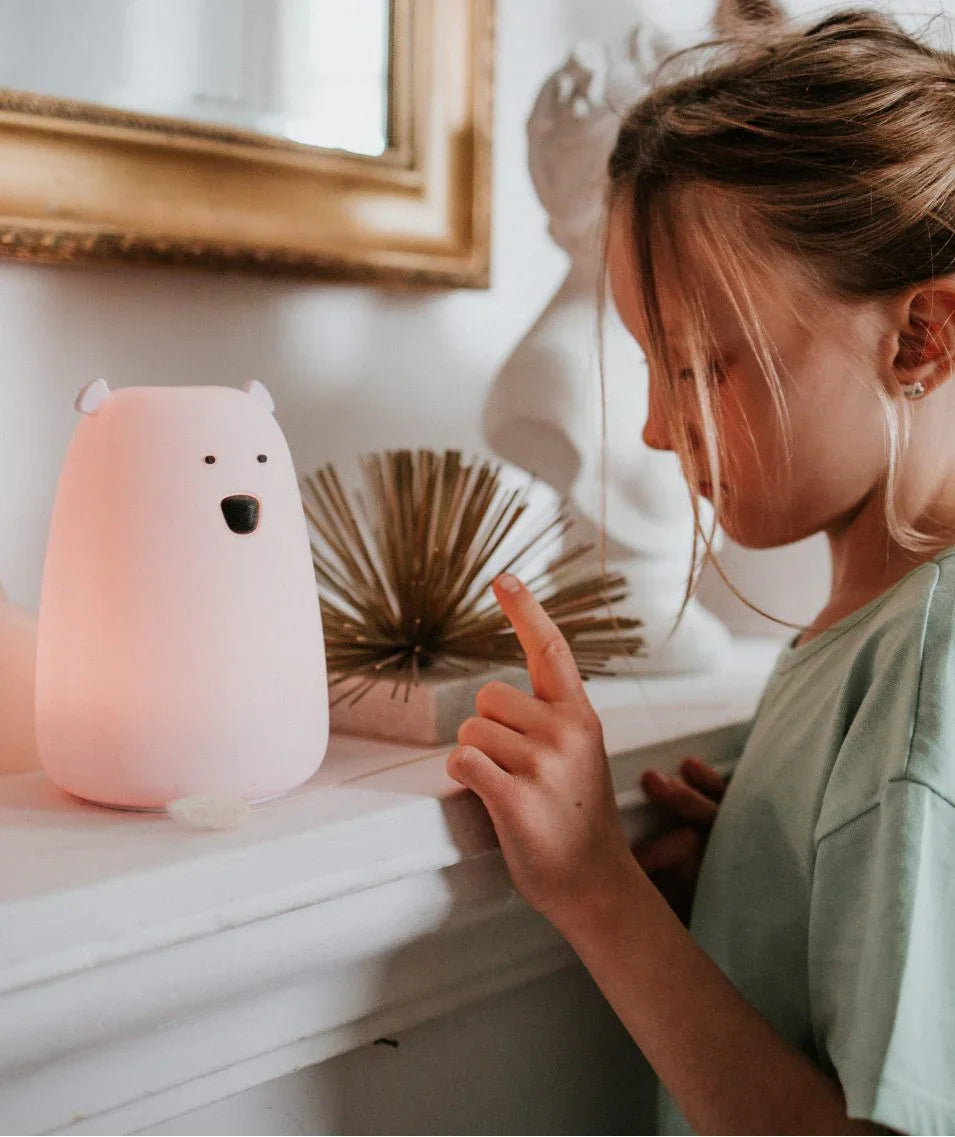 Child interacting with soft glow bear-shaped nursery night light on mantel