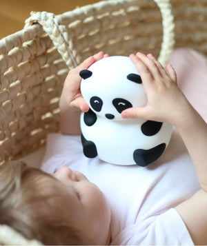 Bébé tenant une veilleuse panda noir et blanc dans son couffin