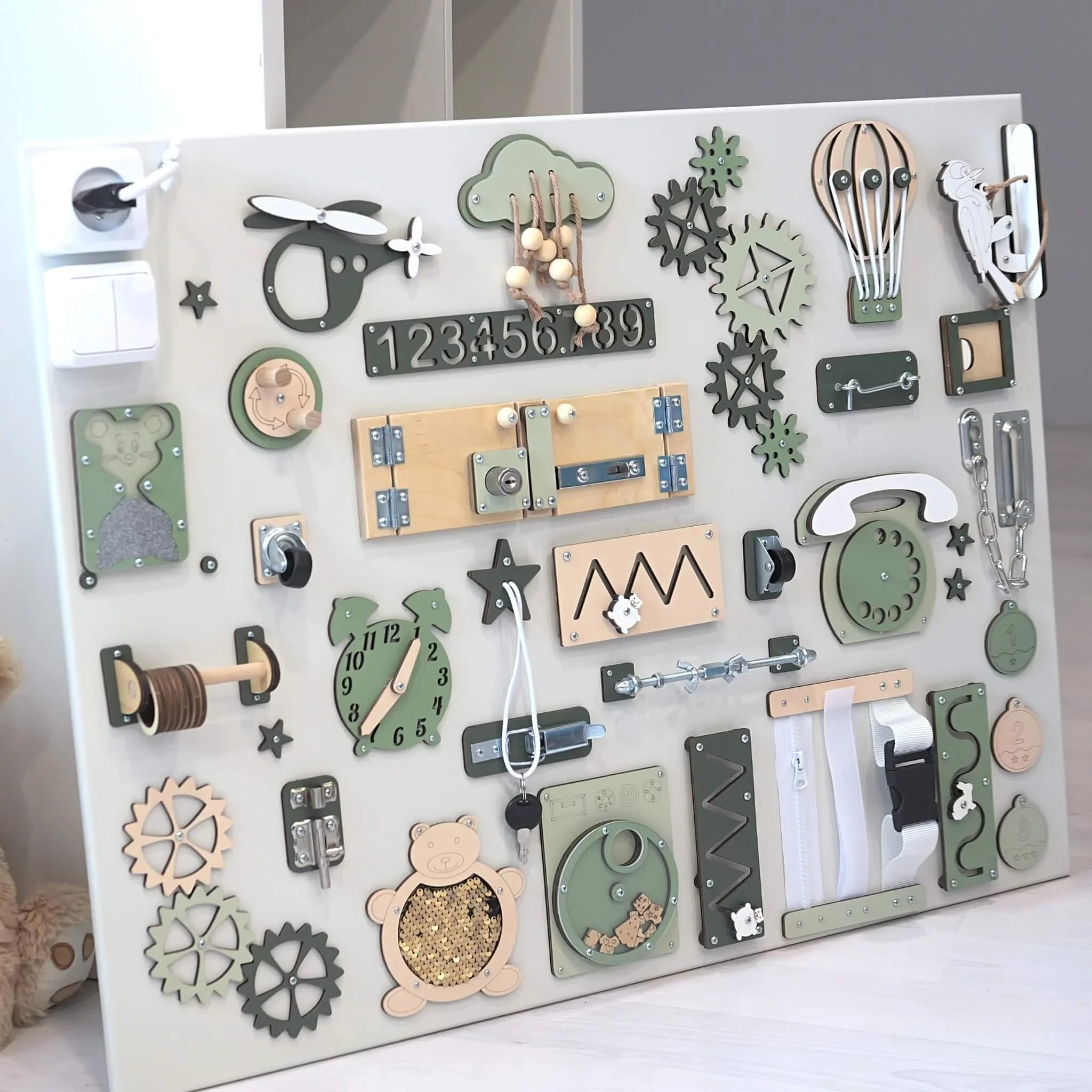 Wooden sensory activity board with gears, zippers, clock, and animal shapes for toddler development