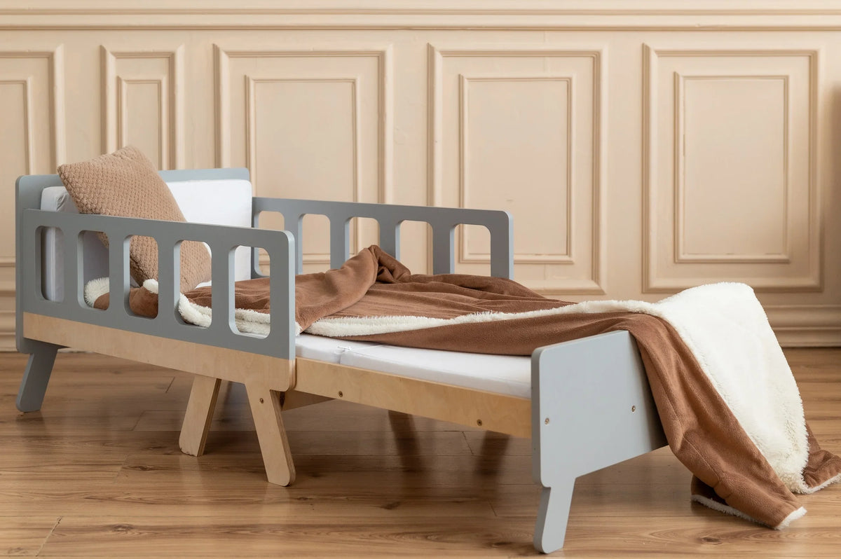 Gray FAMILY Growing Bed fully extended with included white mattress and brown blanket in elegant children’s room