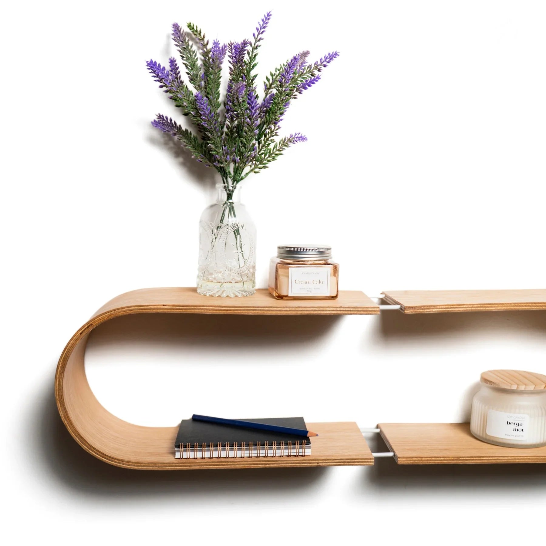 Ovales schwebendes Wandregal mit hellem Holz-Finish, dekoriert mit Blumen im Glas, Kerzen und Notizbüchern