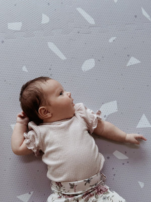 Bébé allongé sur un tapis de jeu puzzle en mousse lavande à motif terrazzo