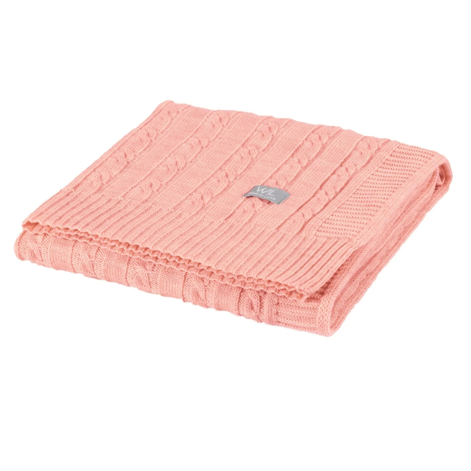 Couverture bébé en tricot torsadé rose saumon pliée avec motif texturé