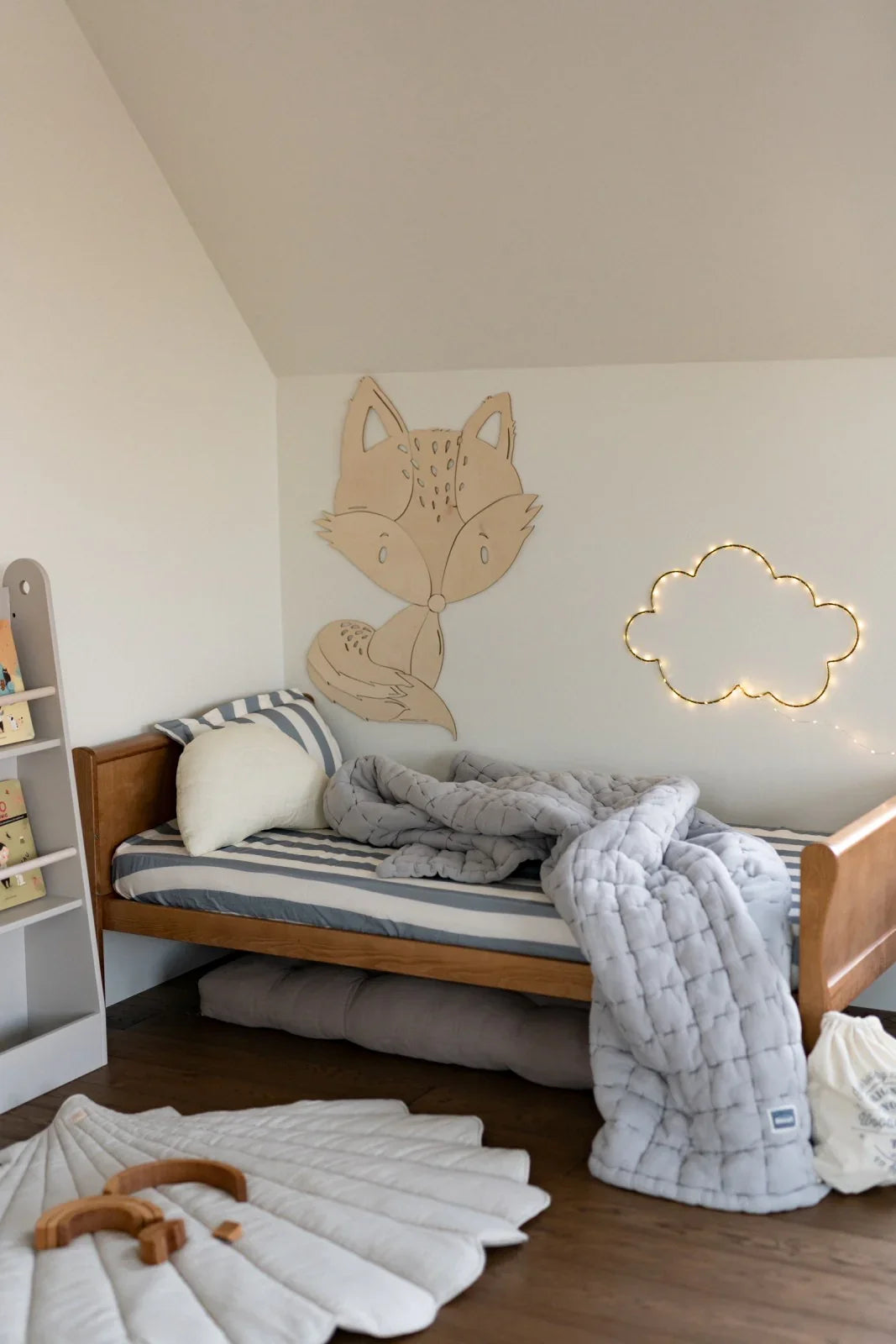 Decorazione da parete in legno a forma di volpe in una cameretta moderna sopra un letto a righe