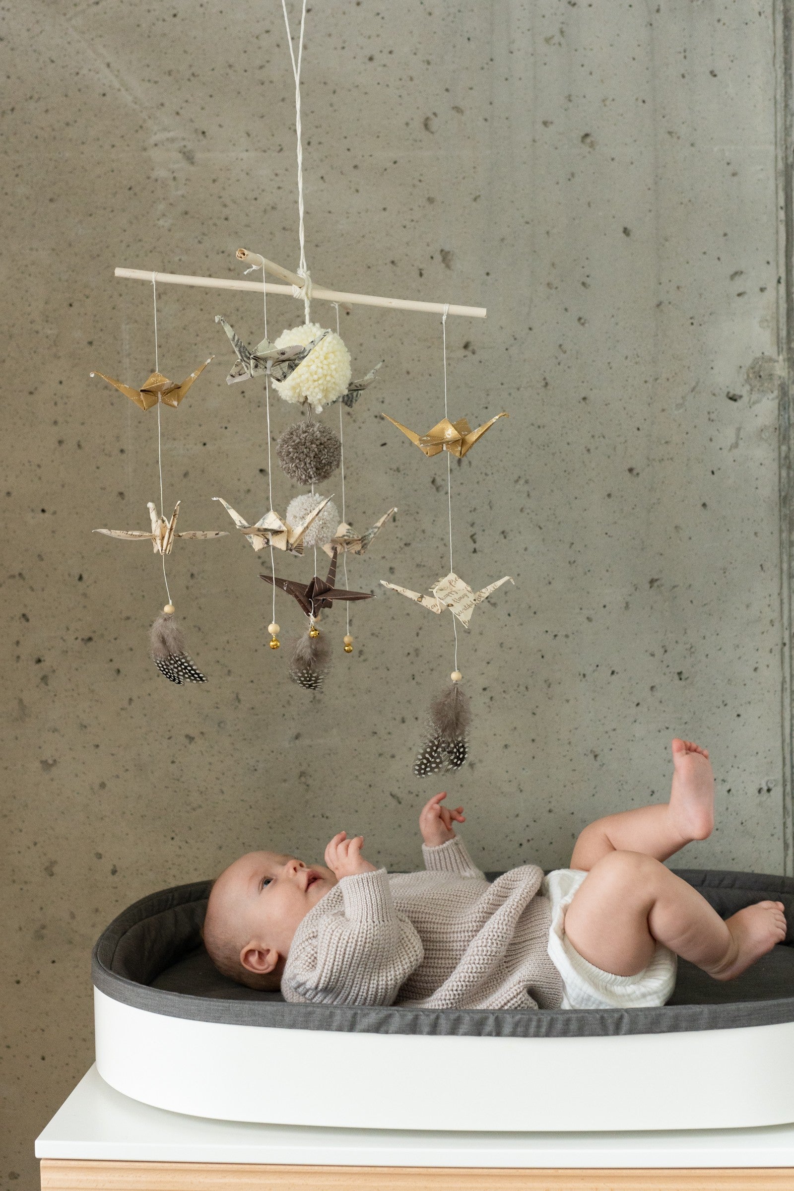 Moi Mili Gold Dust origami nursery mobile hanging above a baby on a changing table