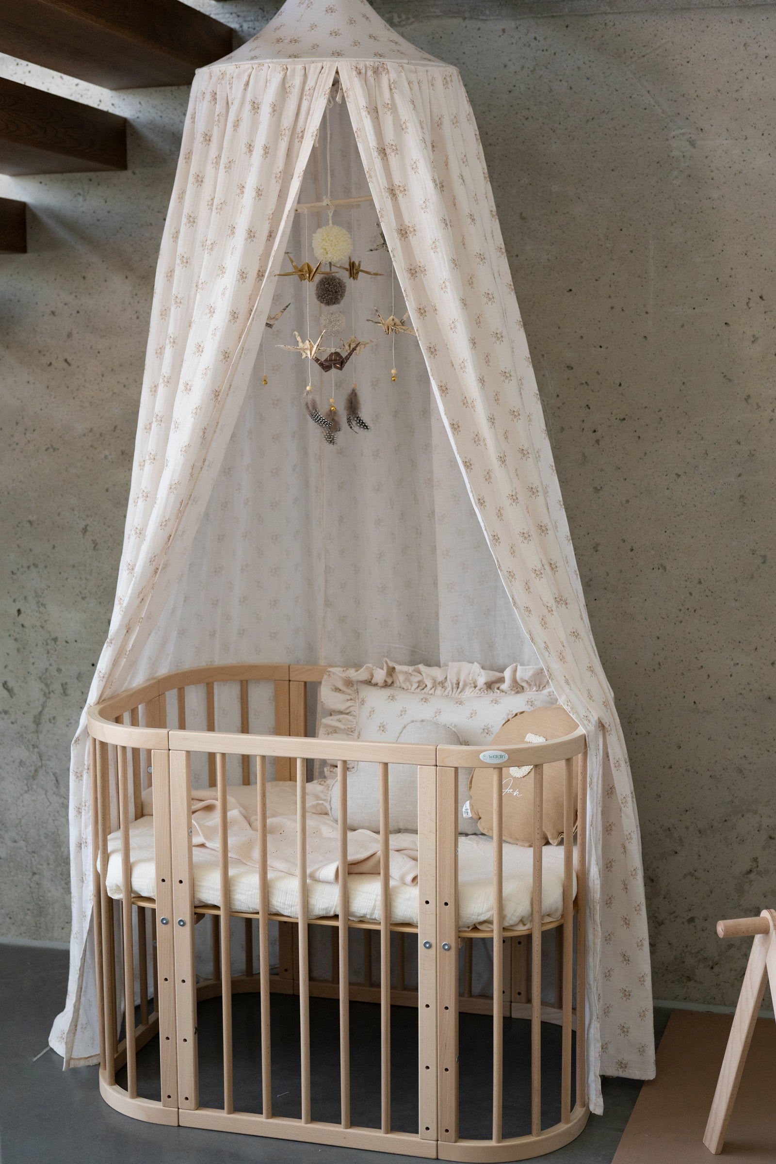 Gold Dust nursery mobile displayed beneath a floral canopy above a natural wooden cot