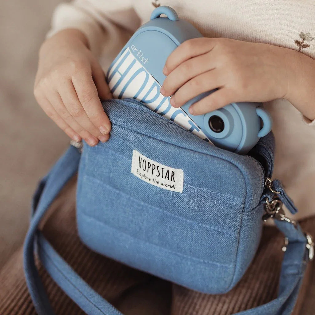 Custodia per fotocamera Hoppstar blu con etichetta frontale, contenente una fotocamera Hoppstar azzurra per bambini