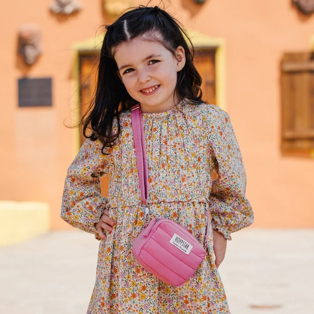 Bambina con vestito a fiori e mini borsa fotografica Hoppstar rosa con tracolla