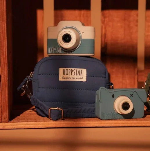 Borsa fotografica Hoppstar blu con fotocamere giocattolo abbinate su mensola in legno, morbido design trapuntato