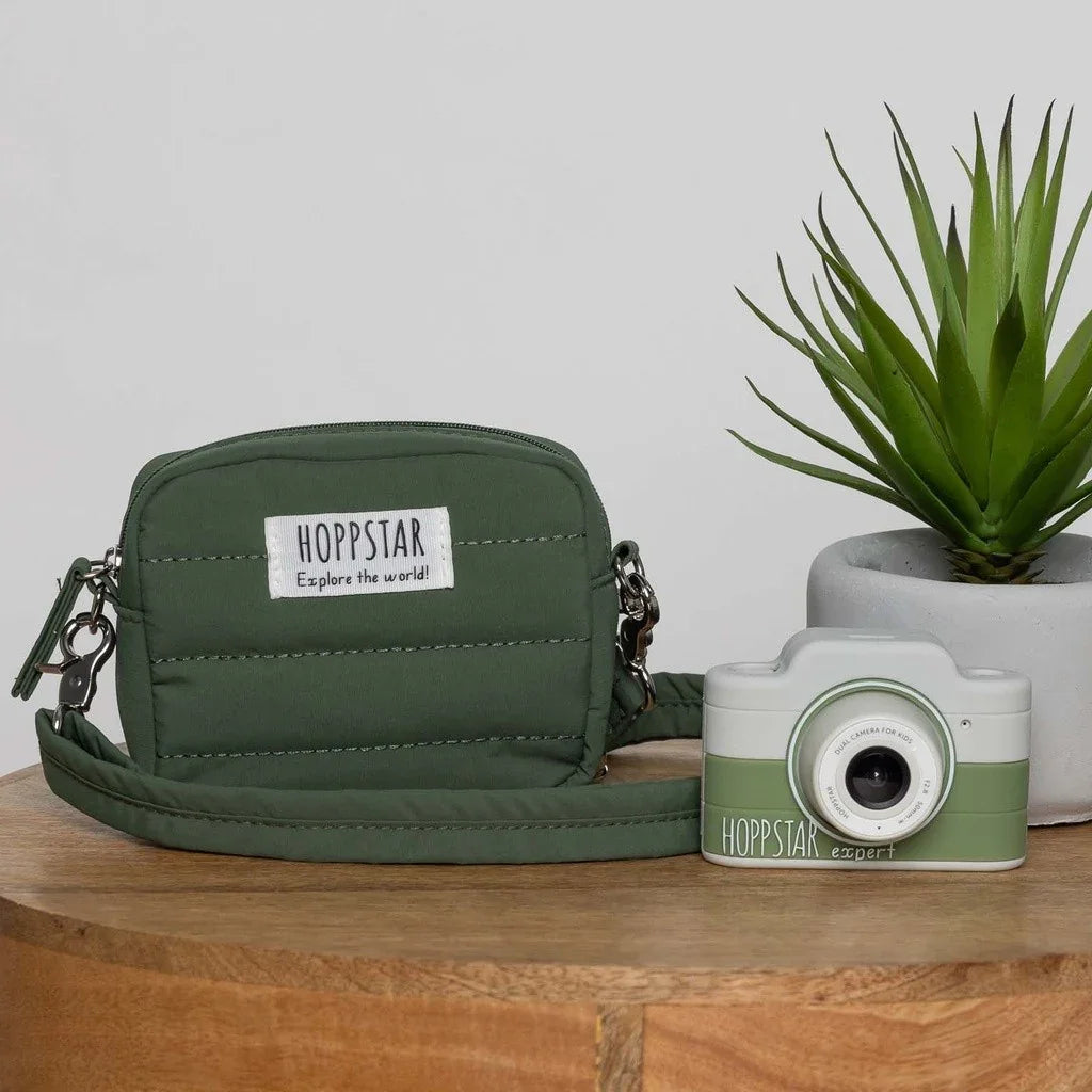 Borsa fotografica Hoppstar verde imbottita e fotocamera digitale per bambini abbinata su tavolo in legno