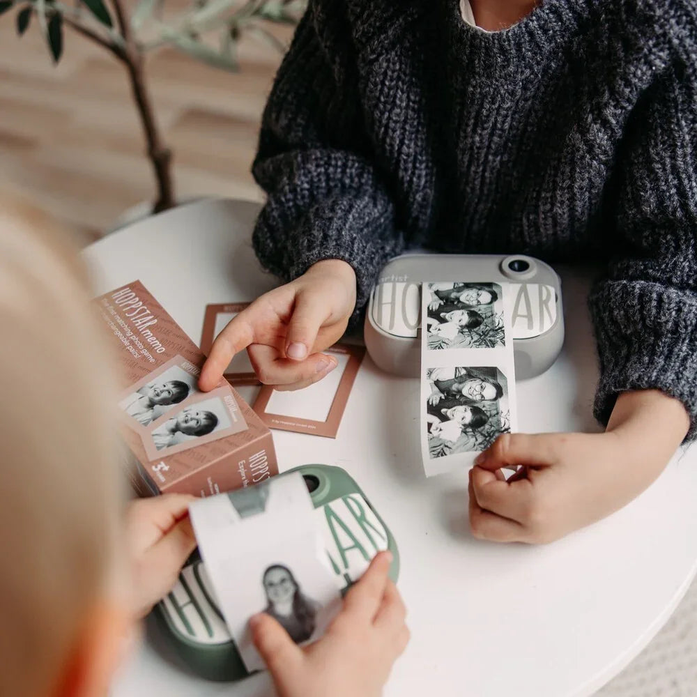 Enfants jouant au jeu de mémoire Hoppstar avec photos instantanées et cartes sur une table