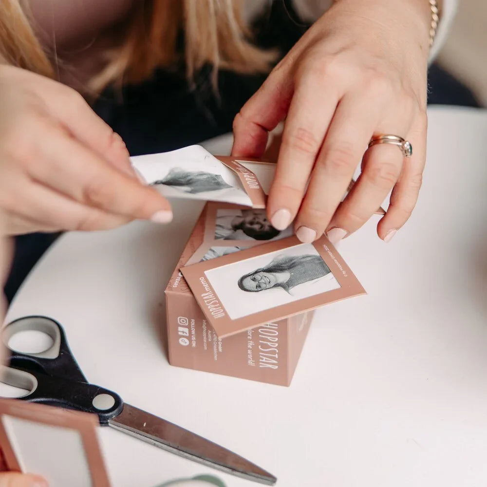 Jeu de mémoire avec cartes illustrées et boîte beige, mains arrangeant les pièces, ciseaux à proximité