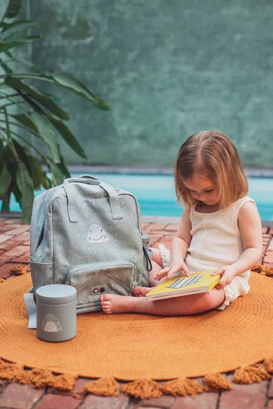 Pot à lunch isotherme 500ml motif requin, à côté d'un sac à dos enfant bleu clair sur tapis orange.