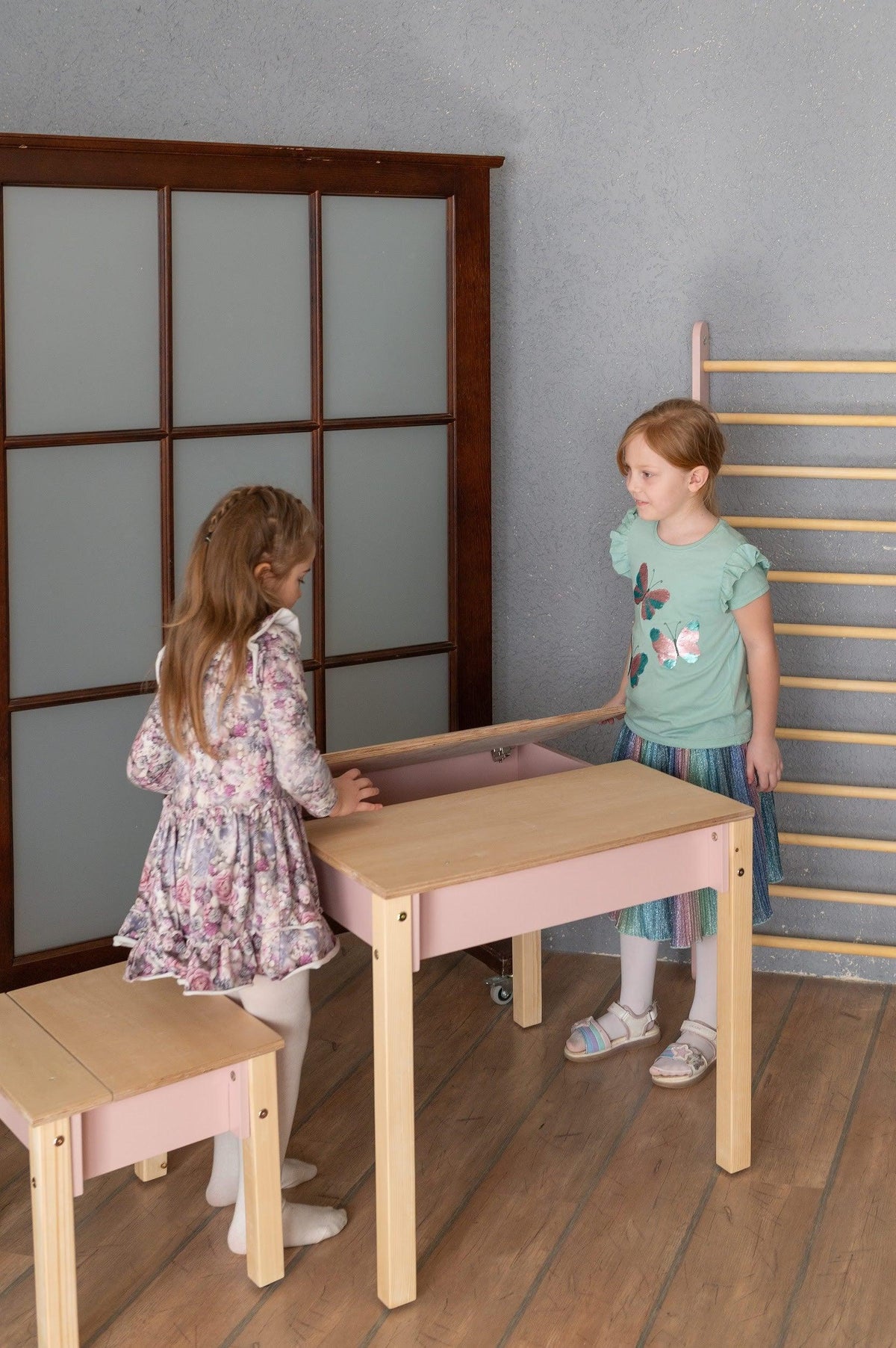 Children organising supplies inside pink Smart Storage Table hidden compartment