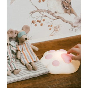 Pink silicone paw-shaped nursery lamp with plush mice toys on wooden surface