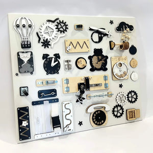 Wooden Montessori activity board with black, white, and natural wood toys including gears, clock, zippers, and latches