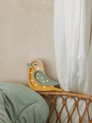 Wooden bird night light with yellow and mint green finish, LED lights, resting on rattan bed frame