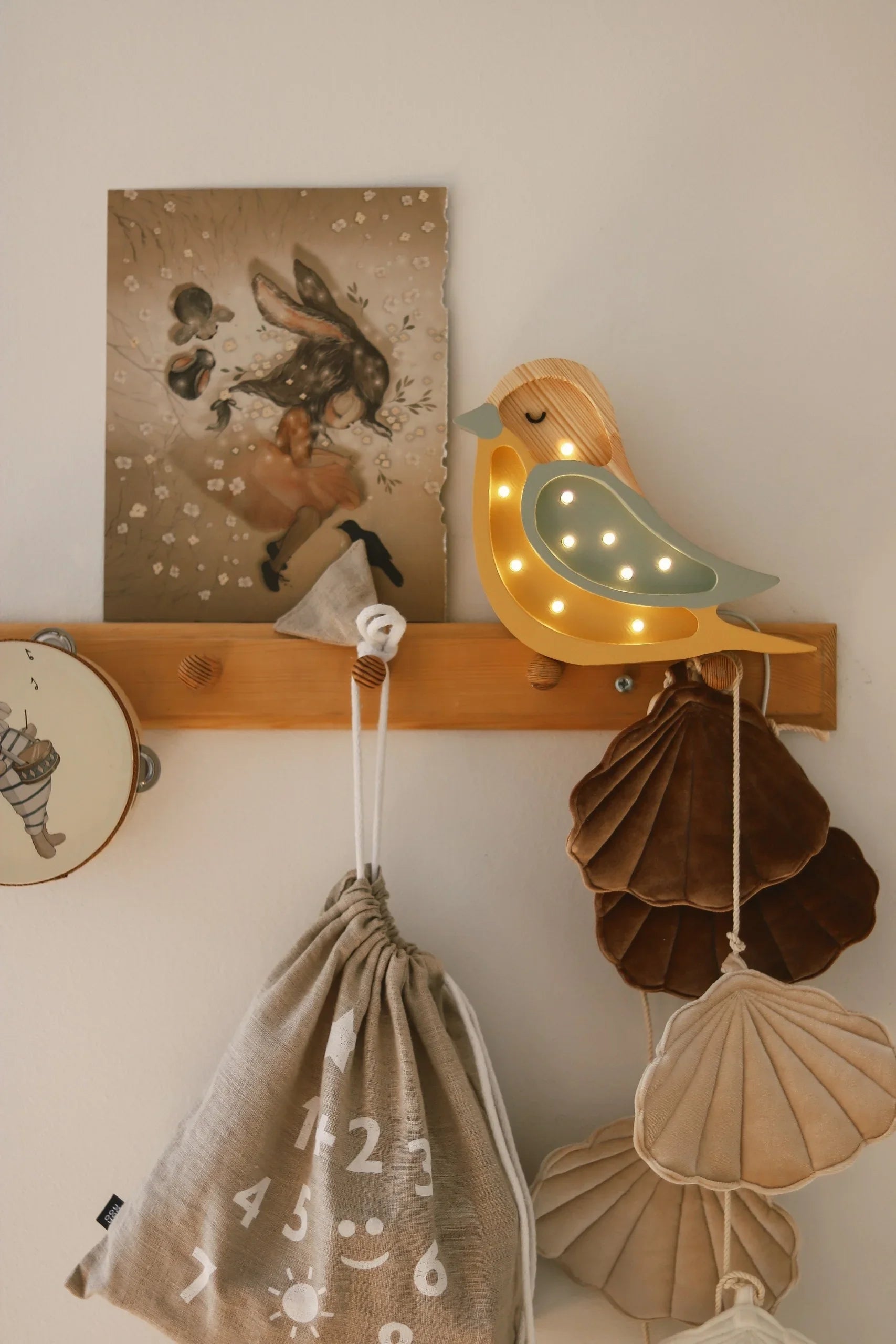Wooden bird night light with warm LEDs, mint accent, mounted on wall above nursery decor and velvet shell ornaments