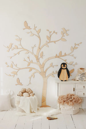 Natural wood wall tree with birds, penguin decor, and nursery accents for modern baby room
