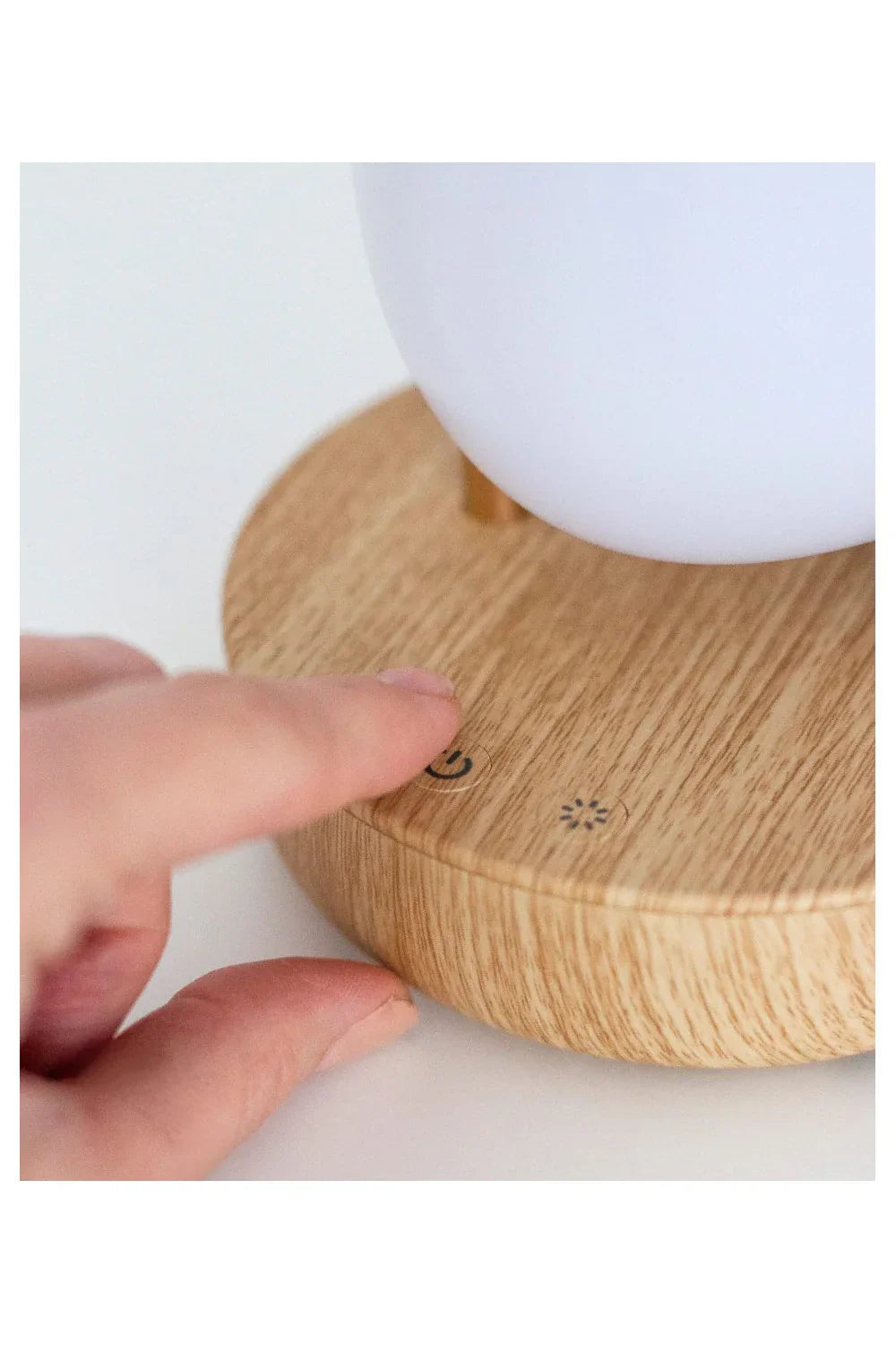 Main appuyant sur le bouton d'alimentation d'une veilleuse moderne effet bois avec commandes tactiles