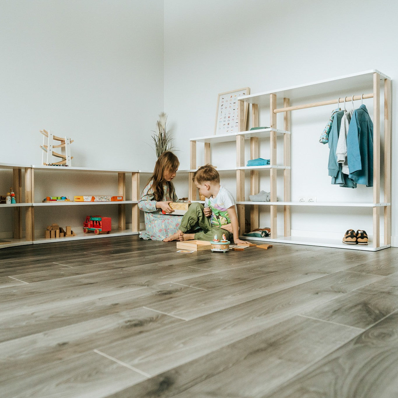 Children playing beside One Little Pine modular shelves, wardrobe and low Montessori storage furniture